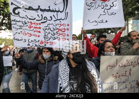 Une militante proteste contre des pancartes et des slogans antigouvernementaux alors qu'elle participe à une manifestation organisée dans la capitale Tunis, pour appeler à la chute du régime et pour protester contre la « violence policière » utilisée lors des dernières manifestations nocturnes qui ont éclaté dans le pays. Ils ont demandé la libération des jeunes manifestants arrêtés par la police. Des manifestants ont également protesté contre la déclaration du président du Conseil de Shura du parti islamiste tunisien Ennahdha, Abdelkarim Harouni, qui a déclaré : « les enfants d'Ennahdha seront sur le terrain pour soutenir les forces de sécurité ». Banque D'Images