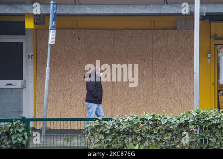 Un homme passe devant une boutique où ses fenêtres ont été écrasées. Les conséquences des troubles anti-couvre-feu à Rotterdam. Fenêtres endommagées de magasins, cafés, chaîne de restauration rapide, chaussée détruite, distributeurs de billets cassés, Les arrêts de bus, les arrêts de tramway, les fenêtres et les lunettes endommagées même dans un quartier résidentiel ont été causés par les violents manifestants qui se sont affrontés avec la police et ont pillé le quartier autour de Groene Hilledijk, Beijerlandselaan et Randweg. C'est la nuit consécutive de 3rd émeutes et affrontements avec les politiques après que le gouvernement a imposé le couvre-feu pour lutter contre la propagation de la pandémie du coronavirus Covid-19 et Banque D'Images
