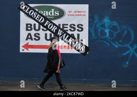 Une femme portant un masque facial marche à côté du panneau « Business as usual » et de l'autocollant « Closed for Walk-In » dans le centre-ville de Dublin pendant le verrouillage Covid-19 de niveau 5. Le mardi 26 janvier 2021, à Dublin, Irlande. (Photo par Artur Widak/NurPhoto) Banque D'Images