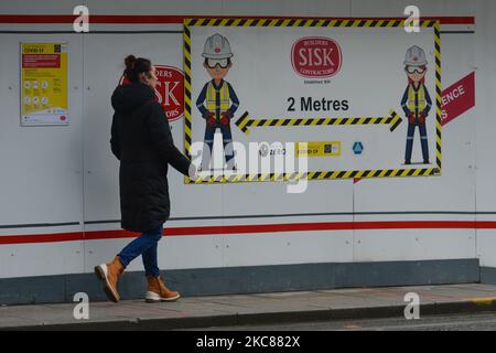 Une femme marche à côté d'un signe de distance social de 2m vu sur un mur à Dublin pendant le verrouillage de niveau 5 Covid-19. Le mardi 26 janvier 2021, à Dublin, Irlande. (Photo par Artur Widak/NurPhoto) Banque D'Images