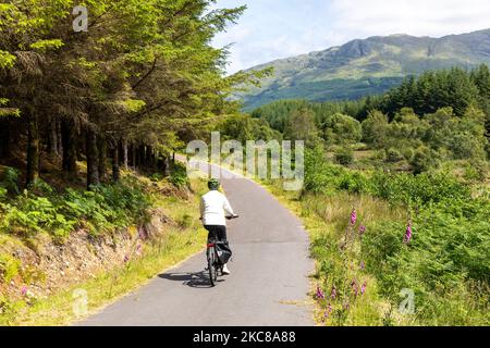 Modèle libéré femme d'âge moyen manèges vélo électrique en Écosse sur la route de vélo de Caledonia Way près d'Oban, Ecosse, Royaume-Uni, été 2022 Banque D'Images