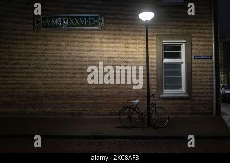 Un vélo sous la lumière pendant la nuit. Rues vides et calmes de la ville néerlandaise d'Amsterdam pendant le couvre-feu COVID. Les gens ne peuvent être dehors qu'avec une raison prouvée et une autorisation spéciale avec la documentation appropriée sinon ils sont condamnés à une amende de 95euro, à l'heure du couvre-feu de nuit. Les transports en commun comme le bus et le tram passent vides. Des policiers et des véhicules ont été déployés à Amsterdam pour donner un aperçu du couvre-feu. Les rues désertes du sont vues au quatrième jour avec le couvre-feu dans le pays, plus calmes après de violentes manifestations et des affrontements les jours précédents. Le couvre-feu a été imposé par le gouvernement pour se battre Banque D'Images