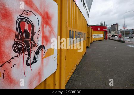 Un signe d'un homme avec un masque de protection chimique vu vandalisé avec des graffitis sur les contenants. Le stade du club PSV de Philips Stadion, situé dans la ville néerlandaise d'Eindhoven, est barricadé de conteneurs d'expédition pour protéger le bâtiment, le musée, le magasin d'air, les portes multiples, le côté piste et les supporters contre les émeutes et le pillage comme cela s'est produit précédemment dans la ville. La fortification et le scellement de l'avant du stade ont eu lieu après que le club a reçu quelques menaces selon les médias locaux. Eindhoven a été confronté à des affrontements violents lors d'une manifestation anti-blocage/anti-couvre-feu qui m'a tourné Banque D'Images