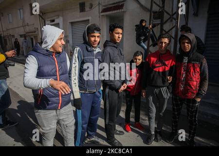 Un groupe d'adolescents d'un quartier difficile sont vus dans la rue de la ville populaire d'Ettadhamen, qui est l'une des villes les plus peuplées de la capitale Tunis. La ville d'Ettadhamen, dont le nom signifie « solidarité », a été formée par les vagues de migrations internes (pauvres, petits agriculteurs et chômeurs) qui ont marqué la Tunisie au début de l'année 1950s. La jeunesse du quartier a joué un rôle central dans la révolution de 2011 qui a renversé le président Zine el-Abidine Ben Ali. Depuis, la situation s'est aggravée : précarité, pauvreté, augmentation du coût de la vie, chômage, abandon scolaire, consommation de drogues, désespoir Banque D'Images