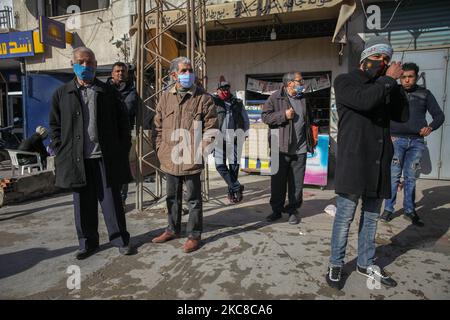 Un groupe de résidents (hommes) d'un quartier dur sont vus dans la rue de la ville populaire d'Ettadhamen, qui est l'une des villes les plus peuplées de la capitale Tunis. La ville d'Ettadhamen, dont le nom signifie « solidarité », a été formée par les vagues de migrations internes (pauvres, petits agriculteurs et chômeurs) qui ont marqué la Tunisie au début de l'année 1950s. La jeunesse du quartier a joué un rôle central dans la révolution de 2011 qui a renversé le président Zine el-Abidine Ben Ali. Depuis, la situation s'est aggravée : précarité, pauvreté, augmentation du coût de la vie, chômage, abandon scolaire, consommation de drogues, saut Banque D'Images