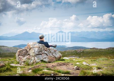 APPLECROSS presqu'île, Highlands d'Ecosse, UK-28 juillet 2022: Un voyageur et randonneur, bénéficie de la vue en milieu d'été, du sommet de la haute montagne col, ov Banque D'Images