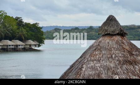 Le toit d'un bâtiment traditionnel de chaume mélanésien du Pacifique Sud donne sur un lagon avec des bungalows de luxe sur l'eau de l'autre côté à Vanuatu Banque D'Images