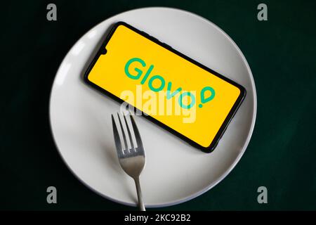 Le logo de l'application Glovo s'affiche sur un écran de téléphone mobile photographié pour illustration sur une plaque et avec des couverts. Cracovie, Pologne sur 9 février 2021. Les chiffres montrent que la pandémie de Covid-19 a entraîné une augmentation importante des repas commandés en ligne par le biais d'applications et de sites Web de livraison de nourriture. (Photo d'illustration par Beata Zawrzel/NurPhoto) Banque D'Images