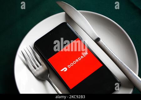 Le logo de l'application Doordash est affiché sur un écran de téléphone mobile photographié pour illustration sur une plaque et avec des couverts. Cracovie, Pologne sur 9 février 2021. Les chiffres montrent que la pandémie de Covid-19 a entraîné une augmentation importante des repas commandés en ligne par le biais d'applications et de sites Web de livraison de nourriture. (Photo d'illustration par Beata Zawrzel/NurPhoto) Banque D'Images