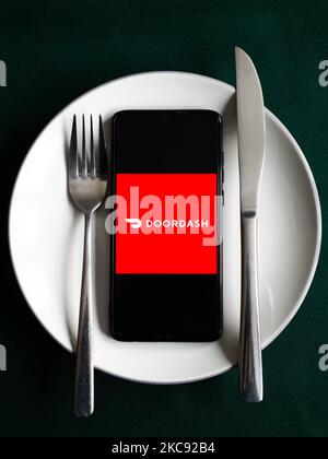 Le logo de l'application Doordash est affiché sur un écran de téléphone mobile photographié pour illustration sur une plaque et avec des couverts. Cracovie, Pologne sur 9 février 2021. Les chiffres montrent que la pandémie de Covid-19 a entraîné une augmentation importante des repas commandés en ligne par le biais d'applications et de sites Web de livraison de nourriture. (Photo d'illustration par Beata Zawrzel/NurPhoto) Banque D'Images