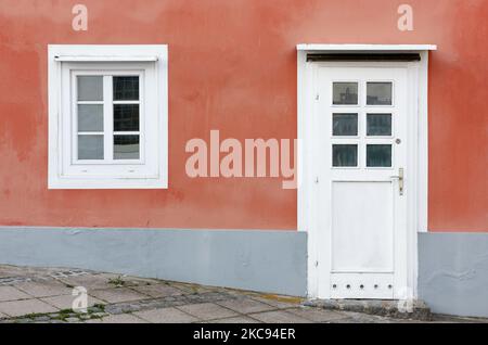 Détail de la façade d'un bâtiment avec le mur peint en orange et une porte et une fenêtre en blanc Banque D'Images