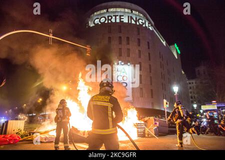 Un pompier est vu sortir le feu de conteneurs devant un bâtiment de la chaîne espagnole du centre commercial, Corte Ingles deuxième nuit de manifestations, à Barcelone, pour la prison du rappeur catalan, Pablo Hasél, arrêté mardi, 16 février et condamné à neuf mois et un jour de prison par la Chambre d'appel de la Cour nationale en septembre 2018, ainsi que le paiement d'une amende d'environ 30 000 euros accusé de glorifier le terrorisme, insulter et calomnier la monarchie et les forces de sécurité de l'état. (Photo par DAX Images/NurPhoto) Banque D'Images