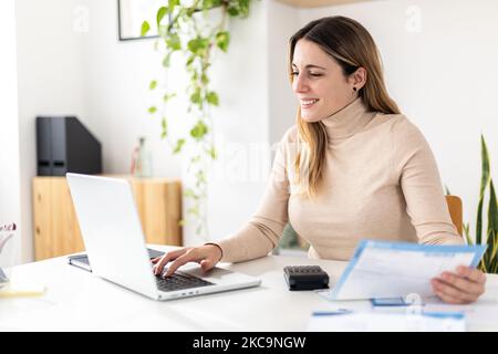 Une jeune femme souriante consulte les factures d'affaires à la réception Banque D'Images