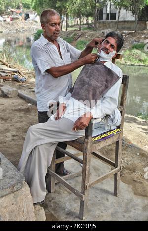 Barber shave un homme à l'extérieur près de la rivière Yamuna dans un bidonville dans le Vieux Delhi, en Inde, sur 10 juin 2014. (Photo de Creative Touch Imaging Ltd./NurPhoto) Banque D'Images