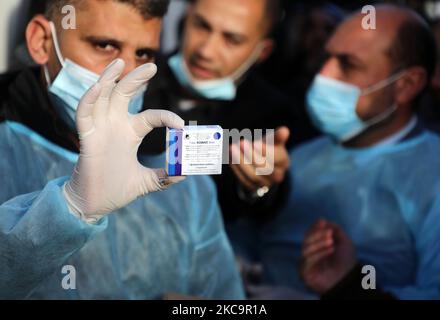 Un agent de santé palestinien porte une boîte de doses de vaccin Spoutnik V de marque russe provenant des Émirats arabes Unis, à l'arrivée d'une charge de camions dans la bande de Gaza via le passage de Rafah avec l'Égypte, sur 21 février 2021. - Environ 20 000 doses de vaccin contre le coronavirus en provenance des Émirats arabes Unis sont arrivées aujourd'hui à Gaza, une livraison aurait été orchestrée par un rival du président palestinien Mahmud Abbas trois mois avant la tenue des élections palestiniennes. (Photo de Majdi Fathi/NurPhoto) Banque D'Images