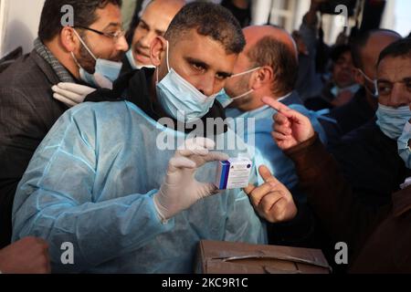 Un agent de santé palestinien porte une boîte de doses de vaccin Spoutnik V de marque russe provenant des Émirats arabes Unis, à l'arrivée d'une charge de camions dans la bande de Gaza via le passage de Rafah avec l'Égypte, sur 21 février 2021. - Environ 20 000 doses de vaccin contre le coronavirus en provenance des Émirats arabes Unis sont arrivées aujourd'hui à Gaza, une livraison aurait été orchestrée par un rival du président palestinien Mahmud Abbas trois mois avant la tenue des élections palestiniennes. (Photo de Majdi Fathi/NurPhoto) Banque D'Images