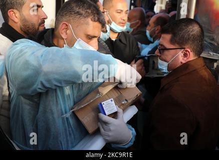 Un agent de santé palestinien porte une boîte de doses de vaccin Spoutnik V de marque russe provenant des Émirats arabes Unis, à l'arrivée d'une charge de camions dans la bande de Gaza via le passage de Rafah avec l'Égypte, sur 21 février 2021. - Environ 20 000 doses de vaccin contre le coronavirus en provenance des Émirats arabes Unis sont arrivées aujourd'hui à Gaza, une livraison aurait été orchestrée par un rival du président palestinien Mahmud Abbas trois mois avant la tenue des élections palestiniennes. (Photo de Majdi Fathi/NurPhoto) Banque D'Images