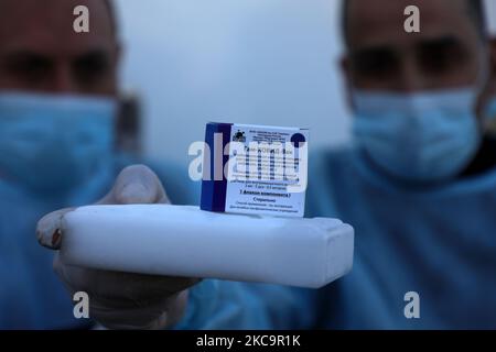 Un agent de santé palestinien porte une boîte de doses de vaccin Spoutnik V de marque russe provenant des Émirats arabes Unis, à l'arrivée d'une charge de camions dans la bande de Gaza via le passage de Rafah avec l'Égypte, sur 21 février 2021. - Environ 20 000 doses de vaccin contre le coronavirus en provenance des Émirats arabes Unis sont arrivées aujourd'hui à Gaza, une livraison aurait été orchestrée par un rival du président palestinien Mahmud Abbas trois mois avant la tenue des élections palestiniennes. (Photo de Majdi Fathi/NurPhoto) Banque D'Images