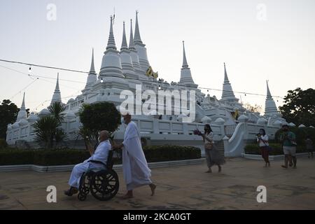 Les personnes qui tiennent des fleurs, des bâtons de jos et des bougies illuminées pour des prières marchent dans un cercle de procession autour du monastère pour marquer la journée de Makha Bucha au temple de Wat Asokaram dans la province de Samut Prakan, Thaïlande, 26 février 2021. (Photo par Anusak Laowilas/NurPhoto) Banque D'Images