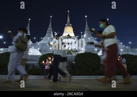 Les personnes qui tiennent des fleurs, des bâtons de jos et des bougies illuminées pour des prières marchent dans un cercle de procession autour du monastère pour marquer la journée de Makha Bucha au temple de Wat Asokaram dans la province de Samut Prakan, Thaïlande, 26 février 2021. (Photo par Anusak Laowilas/NurPhoto) Banque D'Images