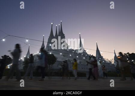 Les personnes qui tiennent des fleurs, des bâtons de jos et des bougies illuminées pour des prières marchent dans un cercle de procession autour du monastère pour marquer la journée de Makha Bucha au temple de Wat Asokaram dans la province de Samut Prakan, Thaïlande, 26 février 2021. (Photo par Anusak Laowilas/NurPhoto) Banque D'Images