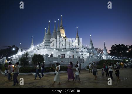 Les personnes qui tiennent des fleurs, des bâtons de jos et des bougies illuminées pour des prières marchent dans un cercle de procession autour du monastère pour marquer la journée de Makha Bucha au temple de Wat Asokaram dans la province de Samut Prakan, Thaïlande, 26 février 2021. (Photo par Anusak Laowilas/NurPhoto) Banque D'Images