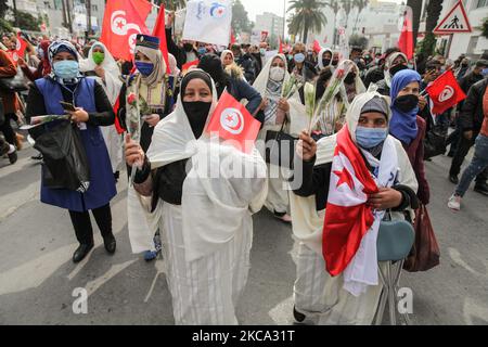 Les partisans voilés d'Ennahda soulèvent des roses alors qu'ils brandisent des drapeaux de Tunisie et des drapeaux d'Ennahda lors d'une manifestation organisée par le parti islamiste d'Ennahda sur l'avenue Mohammed V dans la capitale Tunis, Tunisie, sur 27 février 2021, En faveur de la « légitimité » du Parlement et du gouvernement du premier ministre Hichem Machichi et pour protester contre le rejet par le président Kais Saied du remaniement de Mechichi et pour « protéger la démocratie ». (Photo de Chedly Ben Ibrahim/NurPhoto) Banque D'Images