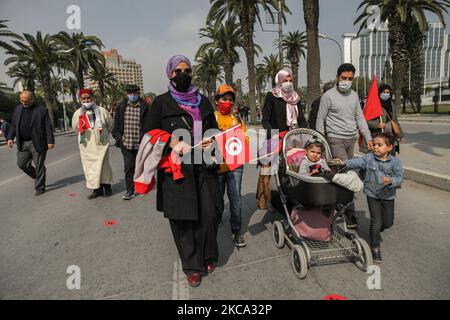 Des membres d'une famille (hommes, femmes, bébés) portant les drapeaux de la Tunisie, vont assister à une manifestation organisée par le parti islamiste d'Ennahda sur l'avenue Mohammed V dans la capitale Tunis, Tunisie, sur 27 février 2021, En faveur de la « légitimité » du Parlement et du gouvernement du premier ministre Hichem Machichi et pour protester contre le rejet par le président Kais Saied du remaniement de Mechichi et pour « protéger la démocratie ». (Photo de Chedly Ben Ibrahim/NurPhoto) Banque D'Images