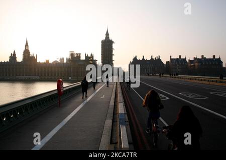 Les cyclistes et les piétons traversent un paisible pont de Westminster tandis que le soleil se couche derrière le Parlement à Londres, en Angleterre, sur 2 mars 2021. (Photo de David Cliff/NurPhoto) Banque D'Images