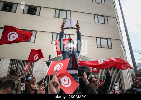 Un manifestant de mouvements islamistes lève une copie du Coran alors que d'autres manifestants branle des drapeaux tunisiens lors d'une manifestation organisée devant le siège de la branche tunisienne de l'Union internationale des boursiers musulmans (IUMS) dans la capitale Tunis, Tunisie, sur 10 mars 2021, Pour protester contre le président du Parti du destin libre (PDL), Abir Moussi et ses partisans, qui tiennent un sit-in à l'extérieur du siège de l'IUMS pour en appeler à sa dissolution. (Photo de Chedly Ben Ibrahim/NurPhoto) Banque D'Images