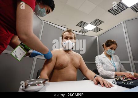 Zenit supporter (C) reçoit une dose du vaccin Spoutnik V contre le COVID-19 dans un centre de vaccination récemment ouvert qui opère dans le stade avant le match de la première Ligue russe entre le FC Zenit Saint-Pétersbourg et le FC Akhmat Grozny sur 13 mars 2021 à l'arène Gazprom de Saint-Pétersbourg, en Russie. (Photo de Mike Kireev/NurPhoto) Banque D'Images