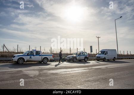 Des voitures de police et des agents de police sont vus en possession de 2 sans-papiers, un d'Afghanistan et un d'Afrique, qui ont franchi illégalement les frontières de la Turquie, sur l'autoroute près de la ville d'Orestiada dans la région d'Evros, Thrace en Grèce. La rivière Evros ou Martisa ou Meric est la frontière extérieure du Sud-est de l'UE et de la zone Schengen. Les demandeurs d'asile sont capturés le long des frontières grecques turques alors qu'ils tentent d'entrer en Grèce et dans l'Union européenne. La police hellénique et les forces de Frontex patrouillent la frontière et capturent quotidiennement, emprisonnent ou arrêtent des migrants, des réfugiés et des passeurs sur le grec - Banque D'Images