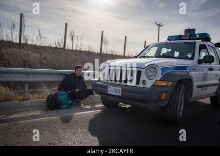Des voitures de police et des agents de police sont vus en possession de 2 sans-papiers, un d'Afghanistan et un d'Afrique, qui ont franchi illégalement les frontières de la Turquie, sur l'autoroute près de la ville d'Orestiada dans la région d'Evros, Thrace en Grèce. La rivière Evros ou Martisa ou Meric est la frontière extérieure du Sud-est de l'UE et de la zone Schengen. Les demandeurs d'asile sont capturés le long des frontières grecques turques alors qu'ils tentent d'entrer en Grèce et dans l'Union européenne. La police hellénique et les forces de Frontex patrouillent la frontière et capturent quotidiennement, emprisonnent ou arrêtent des migrants, des réfugiés et des passeurs sur le grec - Banque D'Images