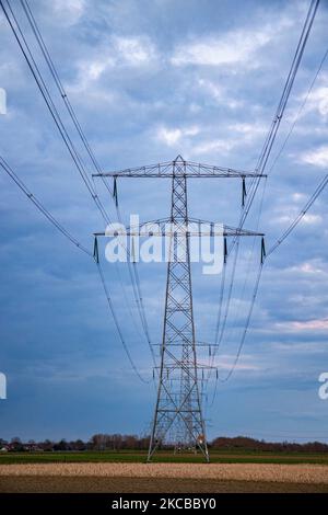 Poteaux électriques haute tension pendant l'heure magique. Les tours métalliques, vues au coucher du soleil dans la campagne hollandaise, distribuent l'énergie électrique de la centrale électrique, de la Belgique et de l'Allemagne à travers le pays. Les fils électriques, la grille et les piliers ou les pylônes de puissance sont vus comme des silhouettes dans le ciel nuageux et coloré de crépuscule. Stevensweert, pays-Bas sur 19 mars 2021 (photo de Nicolas Economou/NurPhoto) Banque D'Images