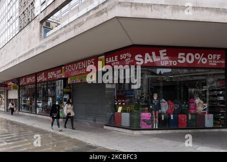 LONDRES, ROYAUME-UNI - 25 MARS 2021 : les gens marchent devant une boutique de souvenirs à volets à Oxford Street alors que l'Angleterre reste sous le troisième confinement pour réduire les taux d'infection de Covid-19, le 25 mars 2021 à Londres, en Angleterre. Le gouvernement a établi un plan pour déverrouiller le pays en quatre étapes au fur et à mesure que le programme de vaccination progresse, avec un assouplissement supplémentaire des restrictions à partir du 29 mars, pour inclure la levée de l'ordre de séjour à la maison, permettant à six personnes de se réunir à l'extérieur et l'ouverture d'installations sportives de plein air. (Photo de Wiktor Szymanowicz/NurPhoto) Banque D'Images