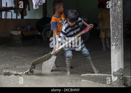 Les enfants nettoient la boue restante qui a frappé leur maison dans le village de Beka, le district de Marawola, la régence de Sigi, la province centrale de Sulawesi, en Indonésie sur 27 mars 2021. Les crues de boue qui se sont produites à 26 mars 2021 cette nuit-là ont été causées par de fortes pluies qui ont causé des glissements de terrain dans les montagnes et ont balayé les colonies dans cette région. Il n'y a pas eu de victimes dans l'incident, mais au moins 70 maisons ont été gravement endommagées, plus de 100 maisons ont été légèrement endommagées et inondées de boue, et environ 200 résidents ont dû être évacués. (Photo de Basri Marzuki/NurPhoto) Banque D'Images