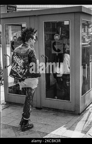 Punk fille attendant devant un téléphone, Berlin Ouest, Allemagne, 1983. Banque D'Images