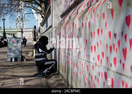 LONDRES, ROYAUME-UNI - 29 MARS 2021 : des volontaires travaillent sur un monument commémoratif pour les victimes de Covid-19 en peignant des coeurs rouges sur un mur à l'extérieur de l'hôpital St Thomas, face au Parlement, le 29 mars 2021 à Londres, en Angleterre. La fresque, créée par Covid-19 Bereaved Families for Justice, une fois achevée, sera composée de près de 150 000 coeurs peints, un pour chaque personne décédée en Grande-Bretagne au cours de la première année de la pandémie, Et devrait s'étendre sur des centaines de mètres le long de la rive sud de la Tamise. (Photo de Wiktor Szymanowicz/NurPhoto) Banque D'Images