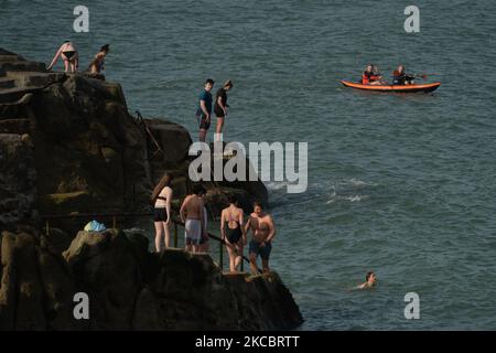 Les canoéistes observent les jeunes nageurs se préparant à sauter dans l'eau à quarante pieds à Sandycove, Dublin, par beau temps, au cours du niveau 5 de verrouillage de COVID-19. Mardi, 30 mars 2021, Sandycove, Dublin, Irlande. (Photo par Artur Widak/NurPhoto) Banque D'Images