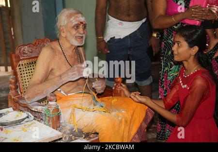 Le prêtre hindou âgé de 92 ans (l'un des prêtres hindous les plus anciens au Sri Lanka) lie un fil sacré au poignet d'une fille tout en bénit les dévotés au Temple hindou Keerimalai Naguleswaram (Thirutambaleswaram Kovil de Keerimalai) situé à Keerimalai, au Sri Lanka. (Photo de Creative Touch Imaging Ltd./NurPhoto) Banque D'Images