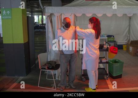 Sous la lumière d'un poêle, une infirmière vaccine un homme de plus de 65 ans convoqué dans le parking de l'hôpital universitaire central des Asturies (HUCA) tandis que d'autres citoyens attendent leur tour. Sur 3 avril 2021, à Oviedo, Asturies, Espagne. (Photo d'Alvaro Fuente/NurPhoto) Banque D'Images