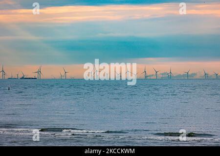 Parc éolien off-shore de moulins à vent générant de l'énergie électrique verte renouvelable à 20 kilomètres de la côte hollandaise entre les pays-Bas et le Royaume-Uni au crépuscule, avec des nuages et des navires au-dessus de l'horizon de la mer. Les générateurs d'éoliennes créent une énergie verte durable à partir de l'énergie éolienne, jet d'air dans l'atmosphère, le parc installé dans la mer du Nord comme vu de Oosterschelde en Zélande aux pays-Bas sur 10 avril 2021 (photo de Nicolas Economou/NurPhoto) Banque D'Images