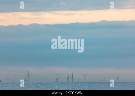 Parc éolien off-shore de moulins à vent générant de l'énergie électrique verte renouvelable à 20 kilomètres de la côte hollandaise entre les pays-Bas et le Royaume-Uni au crépuscule, avec des nuages et des navires au-dessus de l'horizon de la mer. Les générateurs d'éoliennes créent une énergie verte durable à partir de l'énergie éolienne, jet d'air dans l'atmosphère, le parc installé dans la mer du Nord comme vu de Oosterschelde en Zélande aux pays-Bas sur 10 avril 2021 (photo de Nicolas Economou/NurPhoto) Banque D'Images