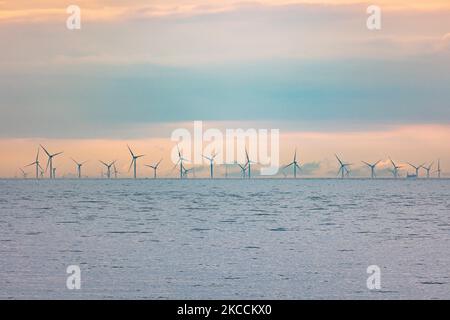 Parc éolien off-shore de moulins à vent générant de l'énergie électrique verte renouvelable à 20 kilomètres de la côte hollandaise entre les pays-Bas et le Royaume-Uni au crépuscule, avec des nuages et des navires au-dessus de l'horizon de la mer. Les générateurs d'éoliennes créent une énergie verte durable à partir de l'énergie éolienne, jet d'air dans l'atmosphère, le parc installé dans la mer du Nord comme vu de Oosterschelde en Zélande aux pays-Bas sur 10 avril 2021 (photo de Nicolas Economou/NurPhoto) Banque D'Images