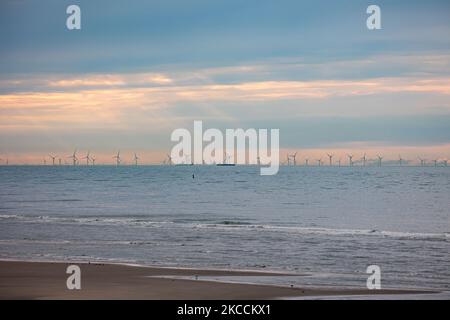 Parc éolien off-shore de moulins à vent générant de l'énergie électrique verte renouvelable à 20 kilomètres de la côte hollandaise entre les pays-Bas et le Royaume-Uni au crépuscule, avec des nuages et des navires au-dessus de l'horizon de la mer. Les générateurs d'éoliennes créent une énergie verte durable à partir de l'énergie éolienne, jet d'air dans l'atmosphère, le parc installé dans la mer du Nord comme vu de Oosterschelde en Zélande aux pays-Bas sur 10 avril 2021 (photo de Nicolas Economou/NurPhoto) Banque D'Images