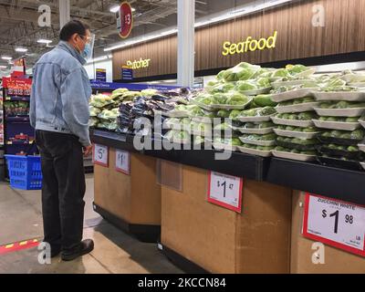 Un homme qui fait des courses dans un magasin Walmart pendant la pandémie du nouveau coronavirus (COVID-19) à Toronto, Ontario, Canada, on 12 avril 2021. Le premier jour de la dernière commande de l'état d'urgence et de séjour à la maison de la COVID-19 en Ontario, les magasins à grande caisse ont été contraints d'adopter de nouvelles mesures pour bloquer les articles jugés non essentiels par le gouvernement provincial. La dernière commande a fermé les petits détaillants pour leurs achats en personne et leur a permis d'offrir uniquement le ramassage ou la livraison sur le trottoir. Cette fois-ci, cependant, les grands détaillants peuvent rester ouverts, mais ne vendre que des produits essentiels comme les épiceries, les biens ménagers Banque D'Images