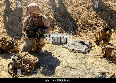 U.S. Marine reprend des tours pour réapprovisionner un tireur de machine. Banque D'Images