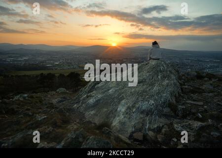 Une femme s'asseoir près du sommet de Bray Head au coucher du soleil, pendant le verrouillage COVID-19. Le jeudi 15 avril 2021, à Bray, comté de Wicklow, Irlande. (Photo par Artur Widak/NurPhoto) Banque D'Images