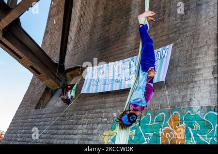 Un acrobat est en train de réaliser de la soie aérienne tandis qu'une bannière XR est suspendue derrière lui, au cours d'une action réalisée par la rébellion d'extinction à Nimègue, sur 16 avril 2021. (Photo par Romy Arroyo Fernandez/NurPhoto) Banque D'Images