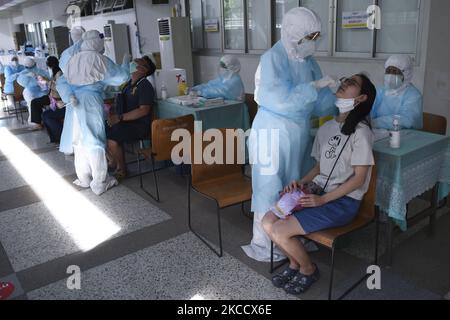 Un travailleur médical portant un EPI effectue un test par écouvillonnage pour le COVID-19 chez une femme lors d'un test par écouvillonnage nasal pour le COVID-19 dans le but d'arrêter la nouvelle vague de pandémie du coronavirus dans un complexe sportif de Bangkok, Thaïlande, 17 avril 2021. (Photo par Anusak Laowilas/NurPhoto) Banque D'Images